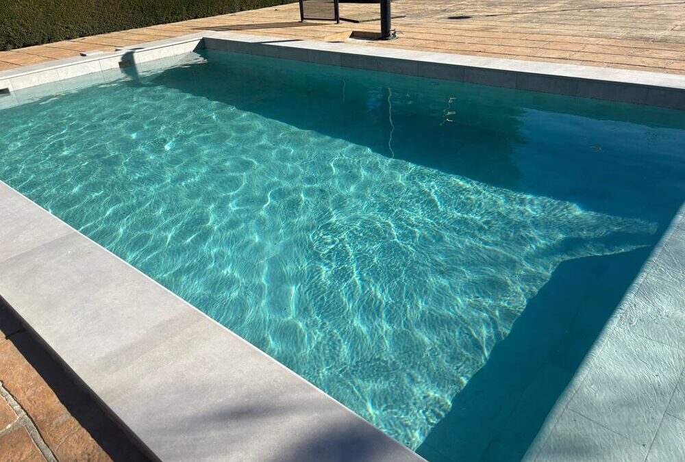 Piscina de porcelánico con escalera rectangular y banco